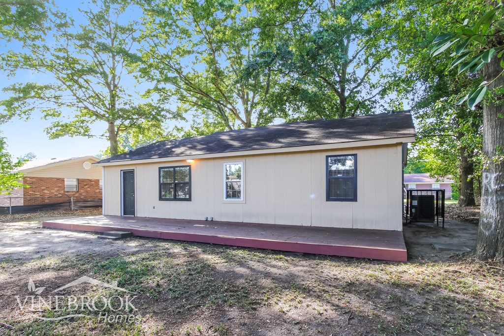 a small white house with a porch and trees